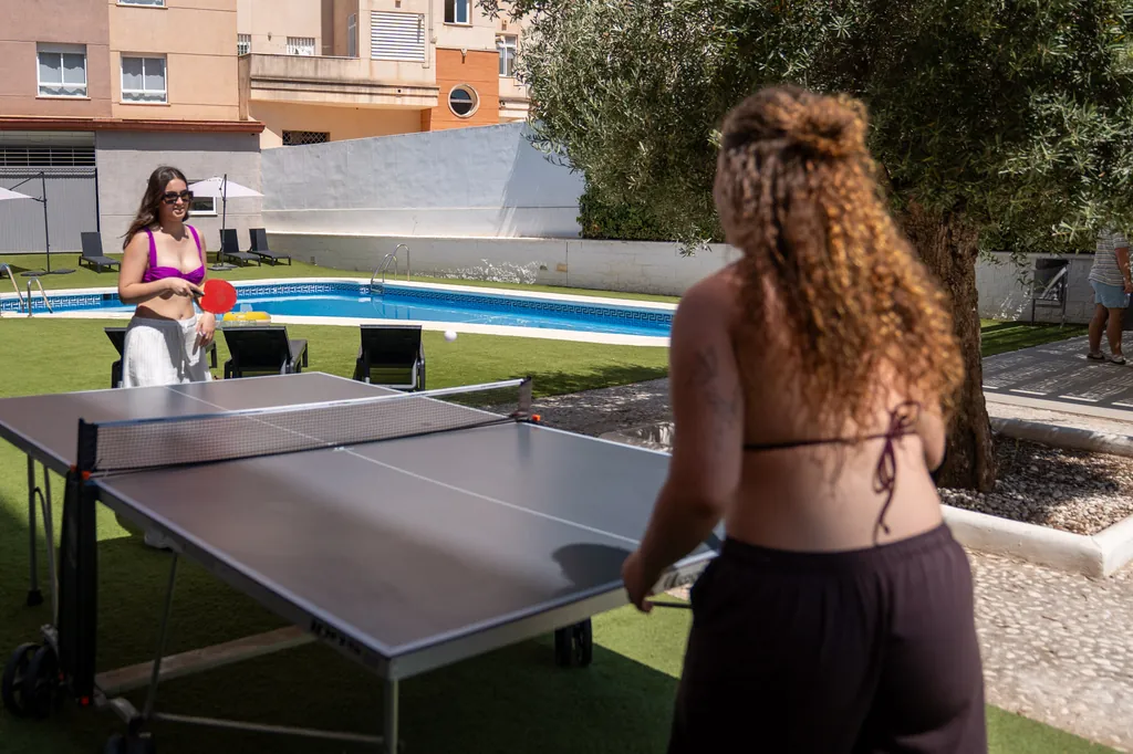 Residentes jugando al ping-pong junto a la piscina